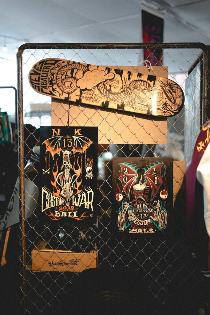 Display of Custom War 2019 posters and intricate skateboard artwork at an indoor event.